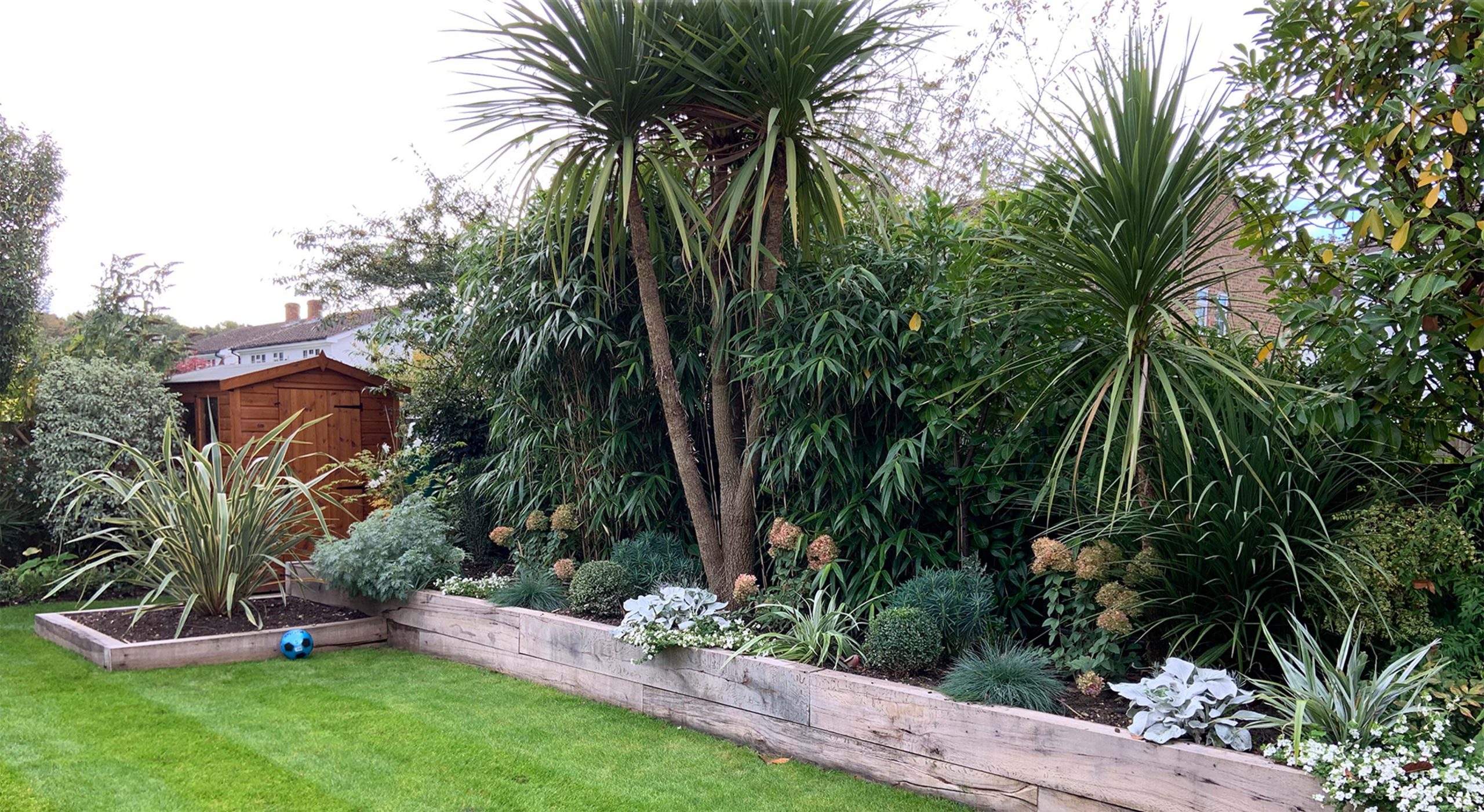 Foliage/ tropical inspired garden with raised beds using a rustic reclaimed sleepers designed by Willow Alexander