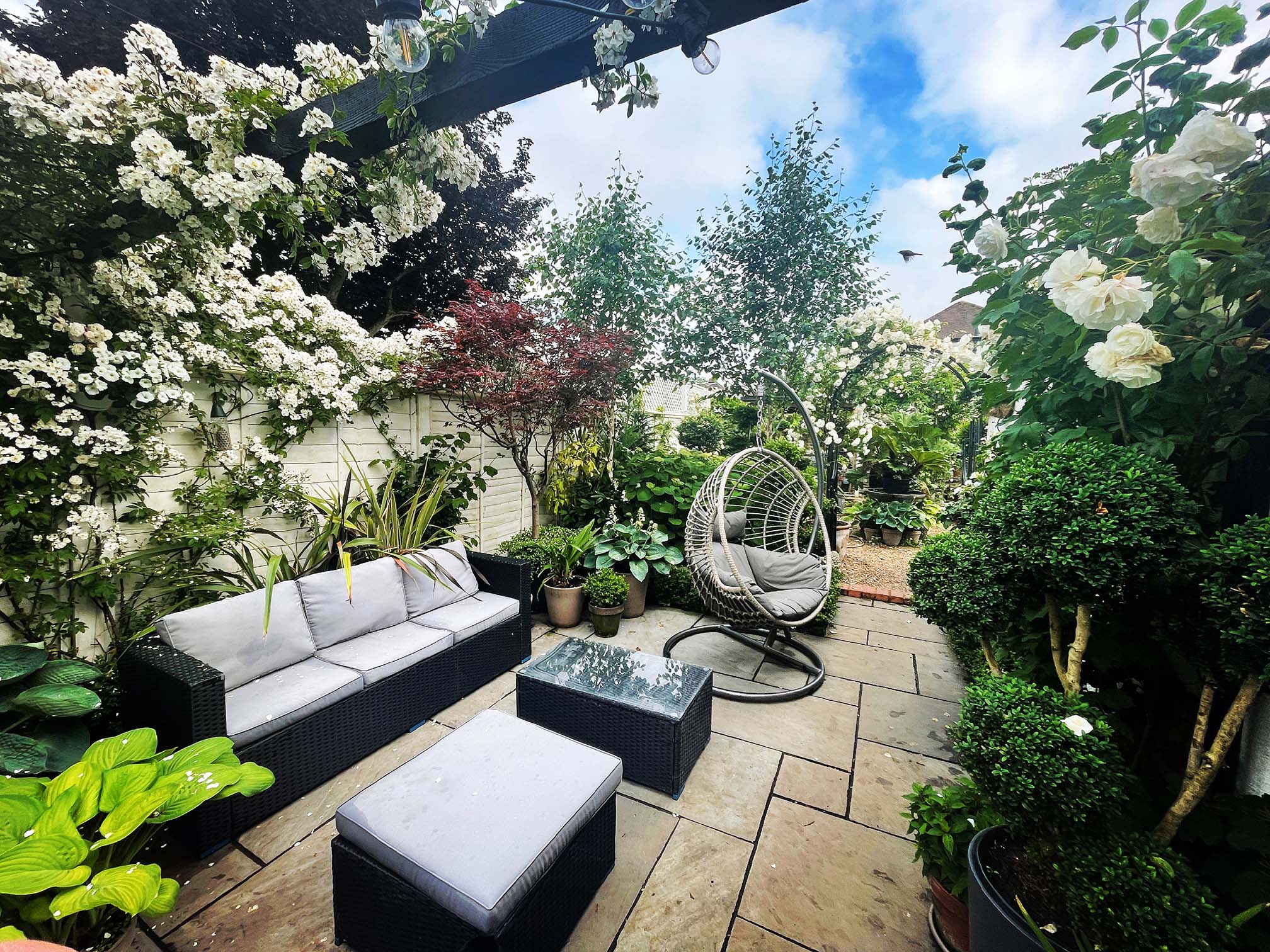 A designer patio surrounded by stunning plants and shrubbery