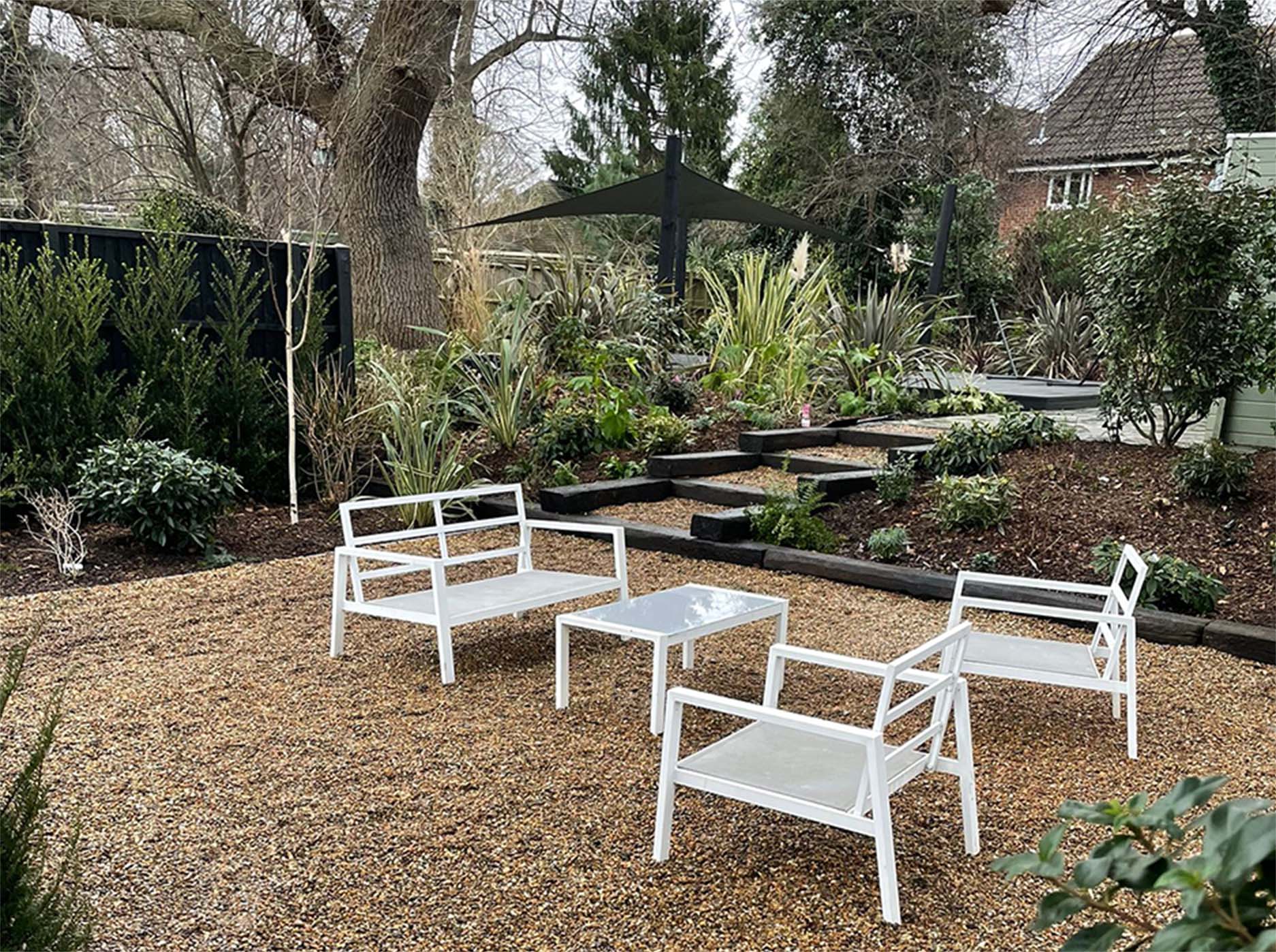 A well kept garden with white furniture in the foreground