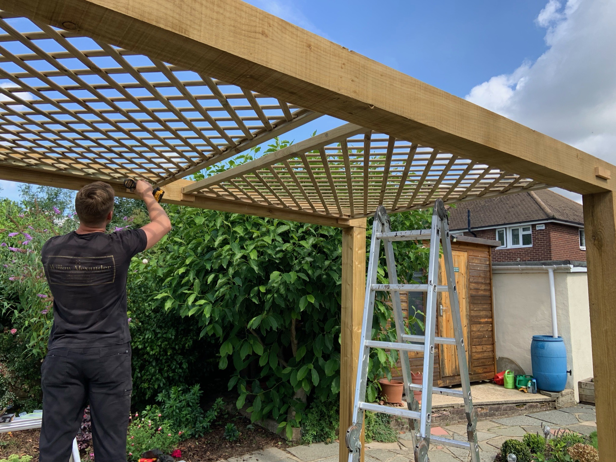 Wooden garden lattice being installed by a member of the Willow Alexander Gardens team